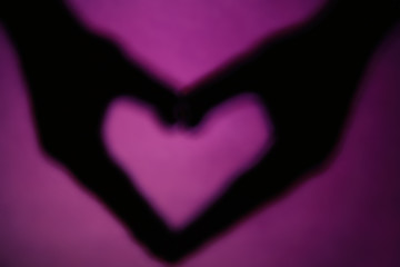 Hand shaped heart on purple background