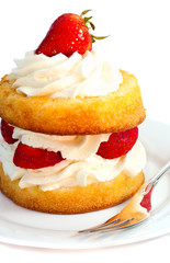 Strawberry shortcake serving on a white plate with silver fork against white background. Close up