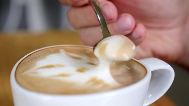 Eating Cappuccino Foam with Spoon in Coffee Shop 