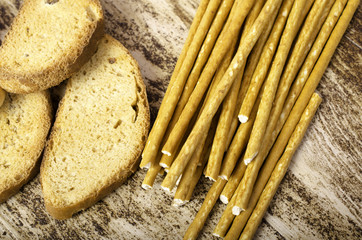 Rusks and sweet sticks horizontally on  background of wood.