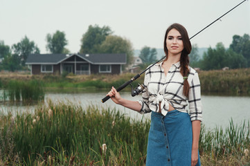  country lady standing against pond on ranch with fish-rod