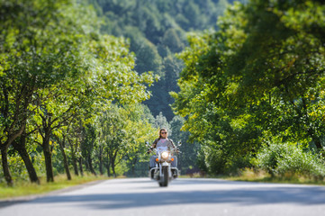 Biker with long hair and beard in sunglasses and leather jacket fast driving on the road in the...