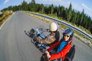 Young man biker riding his motorcycle on the road with the passenger with camera. Selfie style...