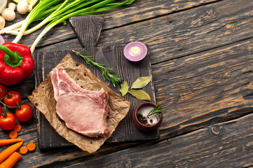 raw bone steak on paper with vegetables