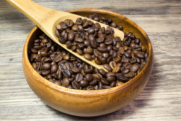 Fototapeta premium Coffee beans in wooden spoon on wooden background