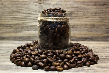 Coffee beans in glass jar on wooden background