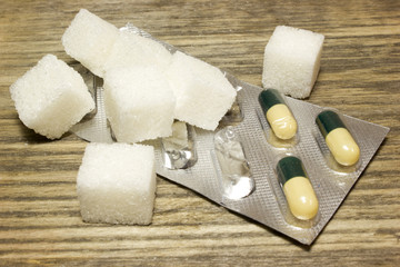 Sugar cubes and tablets on wooden background