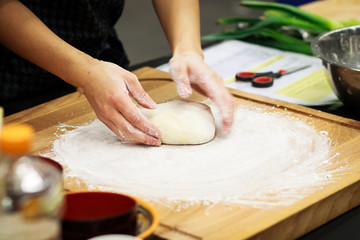 Woman's hands kneading dough on table
