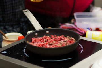 Chef frying minced meat in a pan