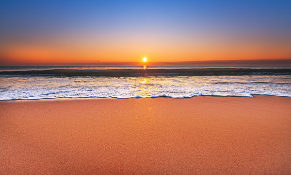 Fototapeta Majestic ocean sunset with a breaking wave.