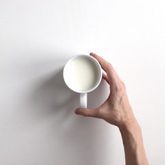 Man's hand takes a cup of milk from table. Top view
