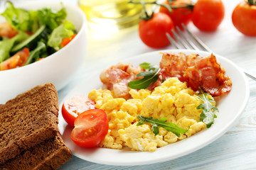 Scrambled eggs with bacon and vegetables on a blue wooden table
