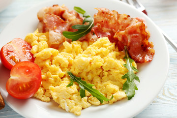 Scrambled eggs with bacon and vegetables on a blue wooden table