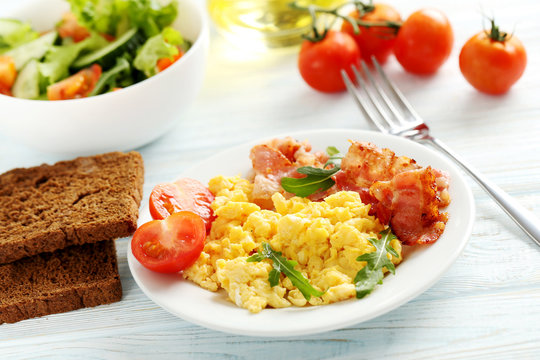 Scrambled eggs with bacon and vegetables on a blue wooden table