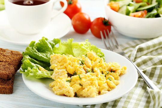 Scrambled eggs with bread and vegetables on a blue wooden table