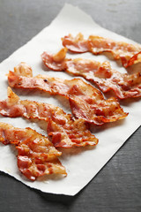 Crispy strips of bacon on a black wooden background
