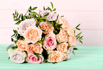Bouquet of beautiful roses on a mint wooden table