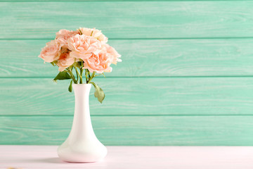 Bouquet of beautiful roses on a pink wooden table