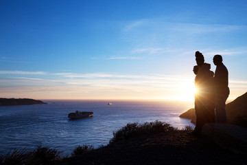 people on bank of sea with sunrise sky