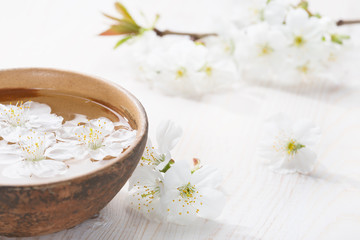 Fototapeta na wymiar Floating flowers ( Cherry blossom) in white bowl. Focus on near flower