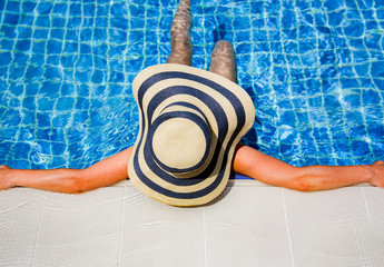 Woman in straw hat relaxing swimming pool