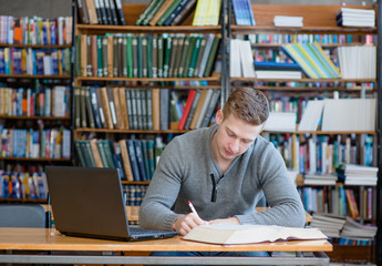 Male student with laptop studying in the university library