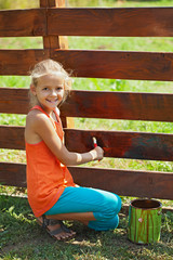 Young girl painting a wooden fence
