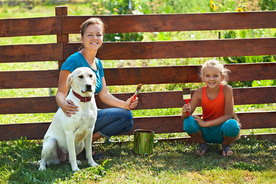 Teamwork - Woman With Little Girl And Dog Painting A Fence