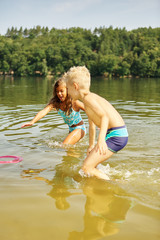 Kinder spielen mit Frisbee im Wasser