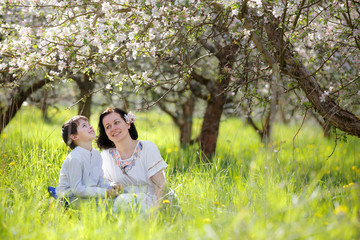 Young woman and her child having rest in spring apple garden