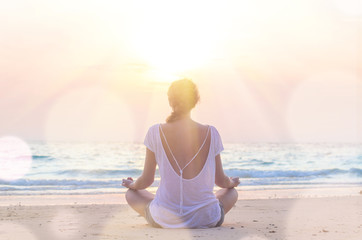 woman practicing yoga at sunrise beach