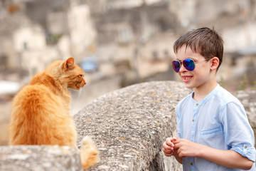 Cute little boy met a cat while walking at typical italian town © levranii