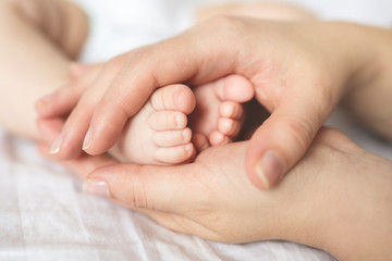Obraz na płótnie Canvas Baby feet in hands of mother