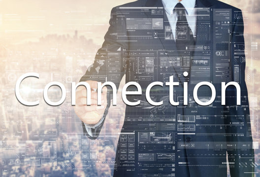 businessman writing Connection on transparent board with city in background