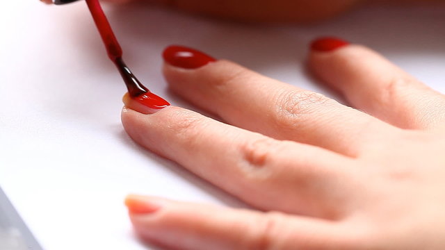 woman paints her nails with red lacquer