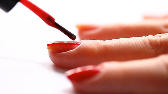 woman paints her nails with red lacquer