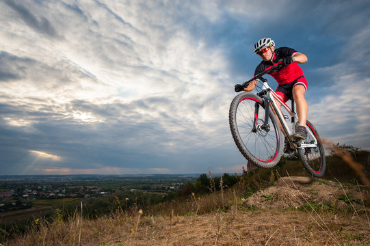 Male mountain biker jumping against blue evening sky. Low angle portrait. Extrem sport downhill cyclist