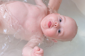 Fototapeta premium Baby care and bathing concept. Washing baby girl in bath.