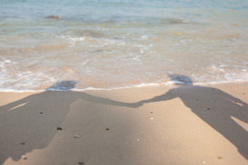 Shadow of young couple holding hands cast on beach sand