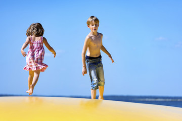 Kinder toben gemeinsam ausgelassen auf einem aufblasbaren Hüpfkissen im Sommer.