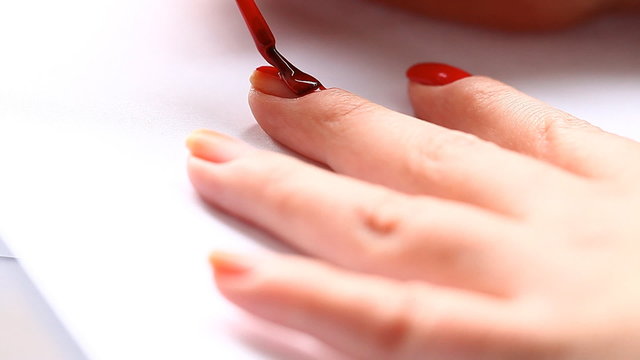 woman paints her nails with red lacquer