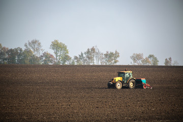Obraz premium Farmer with tractor seeding crops at field