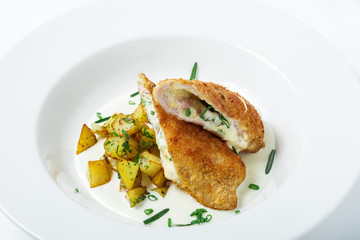 Cutting cordon bleu with cheese, turkey, crackers crumbs, potatoes.