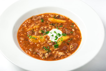 Rassolnik with pickled cucumbers, barley, meat decorated greenery. Close-up