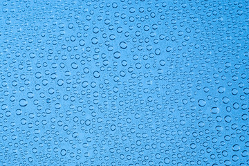 Blue background drops of water on clear glass..