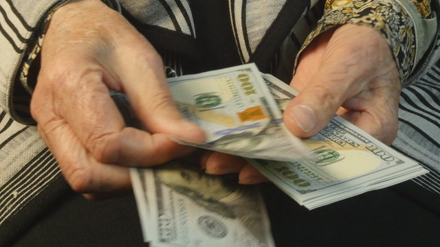 Old woman hands counting hundred dollar bills