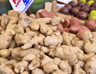 Fresh ginger at a market stall. Weekly market place with fresh vegetables and fruits. Selective focus of ginger in a wooden box at a market stall.