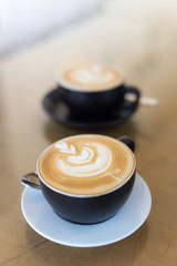 two cup of hot latte art coffee in black mug