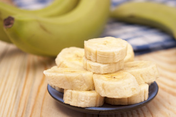 green banana with slices on wooden background