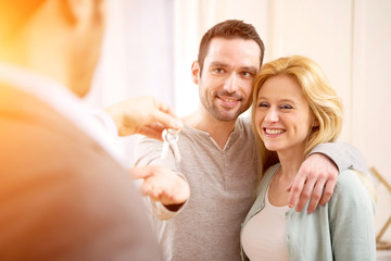 Fototapeta premium Real estate agent delivers keys of new house to young couple